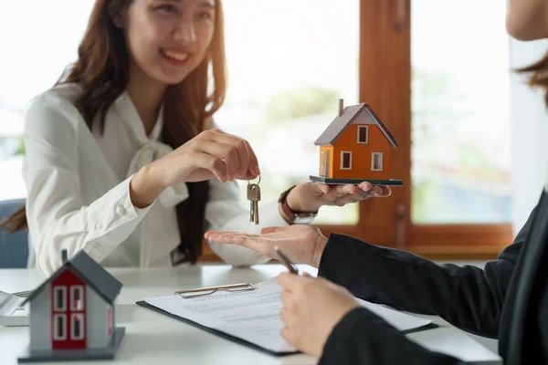 Agente imobiliário segurando casa chave para seu cliente após a assinatura de contrato no escritório, conceito para imóveis, mudança de casa ou arrendamento de propriedade — Fotografia de Stock