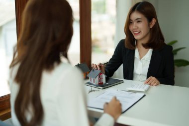 Emlakçı veya banka memuru, konut satın alma sözleşmesi veya ofis kredileri ve faiz oranları olan müşteriye kredi faizini açıklar.