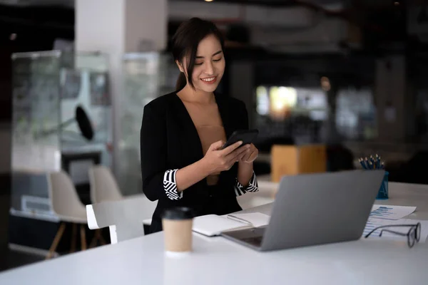 Mulher asiática de negócios usando telefone celular durante a verificação de um e-mail ou mídia social na internet. conceito financeiro contabilístico. — Fotografia de Stock