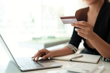 Asyalı kız evde alışveriş yapmak için laptop ve kredi kartı kullanıyor.