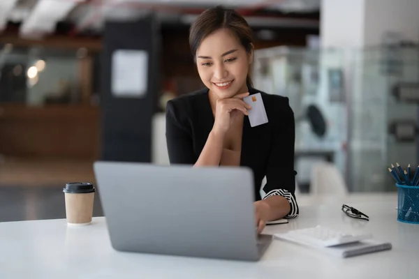 Chica asiática haciendo pago en línea utilizando el ordenador portátil y tarjeta de crédito para ir de compras en casa —  Fotos de Stock