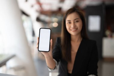 Güzel bir Asyalı kadının görüntüsü. Cep telefonunu beyaz ekranla gösteriyor.