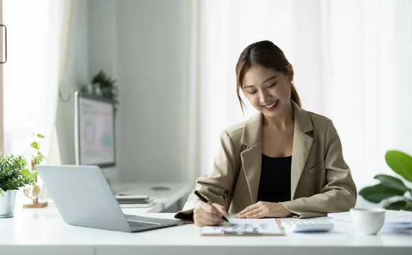 Ofisteki ahşap masa, vergi, muhasebe ve finansal konsebe üzerinde matematik finansmanı için dizüstü bilgisayar kullanan Asyalı bir kadın. — Stok fotoğraf