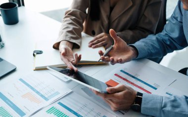 Dijital tablet ve evrak işleriyle ilgili finansal planlamayı tartışan iki iş ortağını kapat.