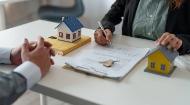 Emlakçı müşteriye ev modeliyle kontrat imzalaması için yardım ediyor.