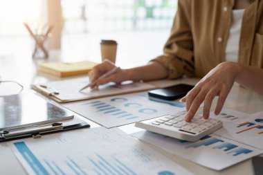 İş kadını ya da muhasebecinin, iş verilerini, muhasebe belgelerini ve ofisteki dizüstü bilgisayarları, iş konseptini hesaplamak için hesap makinesi üzerinde çalışmasını kapat