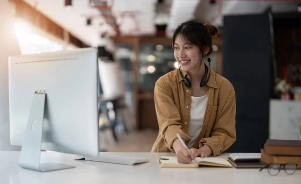 ラップトップ画面を見てヘッドセットを使用して笑顔アジアの若い女性は、オンラインコースを聞いて学習します。顧客サービスのためのヘッドフォンビデオコールを持つ幸せなビジネス女性 — ストック写真