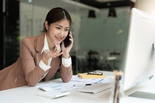 아시아 회계사들은 스마트폰을 이용하여 마케팅 컨설턴트들에게 전화를 걸고 노트북 컴퓨터를 이용하여 세계 직장 시장의 매출 증가를 분석 합니다. 회계 개념 — 스톡 사진