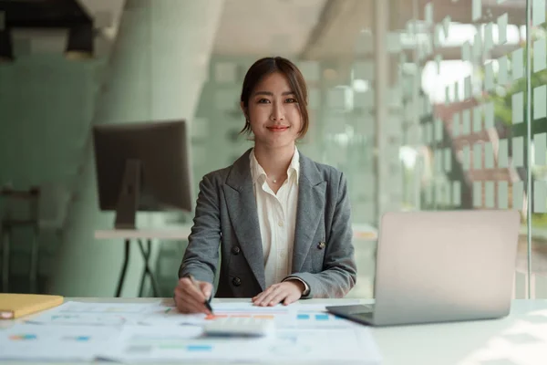 Portret aziatische vrouw werken voor de financiële boekhouding met rekenmachine en laptop computer in het kantoor — Stockfoto