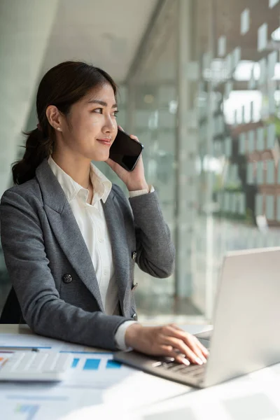 Confiado negocio asiático mujer en hablar consultor en el teléfono móvil en la oficina moderna — Foto de Stock