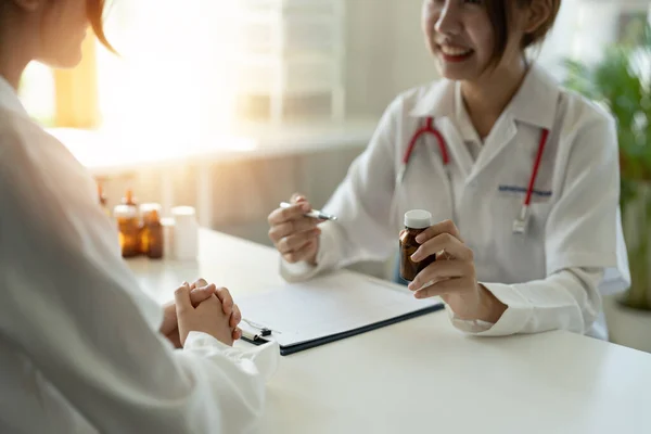 Vrouwelijke arts geeft pillen fles aan patiënt in de kliniek. Begrip gezondheidszorg, medische behandeling en verzekering — Stockfoto