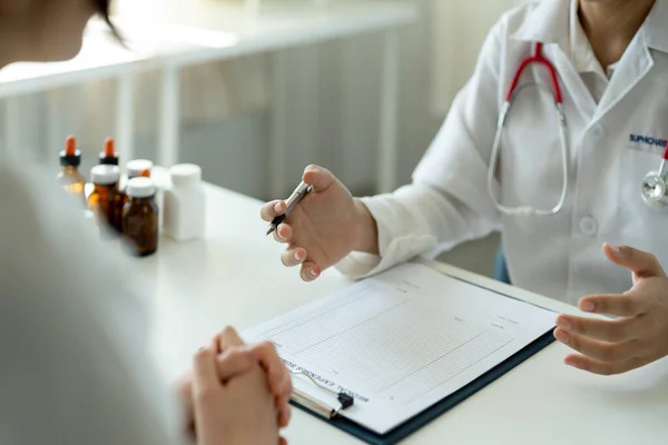 Asian female doctor in white medical uniform consult female patient in private hospital. woman therapist speak talk with woman client on consultation in clinic —  Fotos de Stock