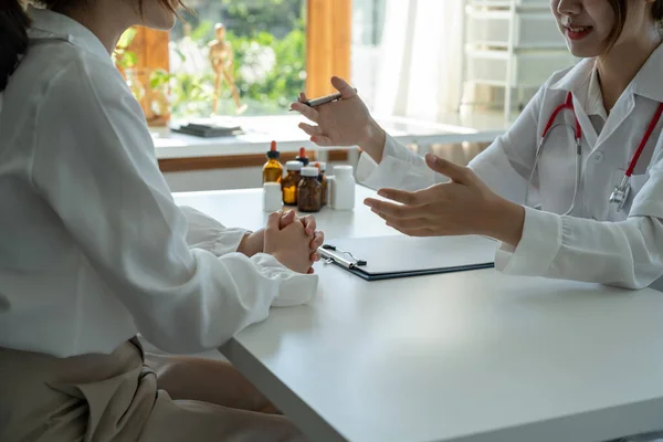 Aziatische vrouwelijke arts in wit medisch uniform te raadplegen vrouwelijke patiënt in prive-ziekenhuis. vrouw therapeut spreken met vrouw cliënt op consult in kliniek — Stockfoto