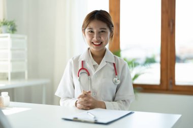Steteskoplu gülümseyen kadın doktorun portresi klinikte oturuyor.
