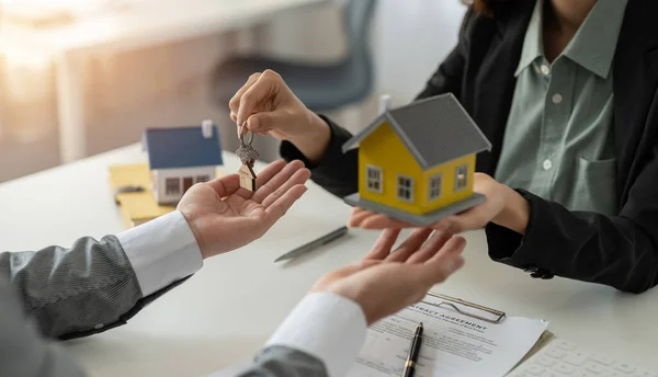 Mannen tar nycklar från kvinnliga fastighetsmäklare under mötet efter att ha undertecknat hyresavtal eller köpeavtal. Självständig kvinna köper nytt hem — Stockfoto