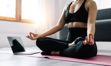Egzersiz yapan genç bir kadın, laptopta, yogada ve sağlıklı yaşam tarzında meditasyon yapan Asyalı bir kadın..