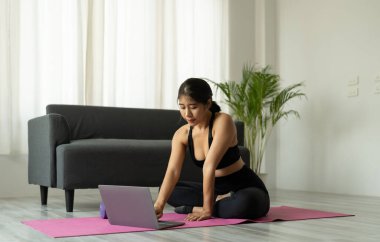 Yoga stüdyosunda dizüstü bilgisayarı olan Asyalı kadın - fitness, teknoloji ve sağlıklı yaşam tarzı konsepti