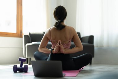 Yoga yapan, Vajrasana pozu veren, Namaste 'nin arkasında oturan, spor kıyafeti giymiş genç bir Yogi kadını..