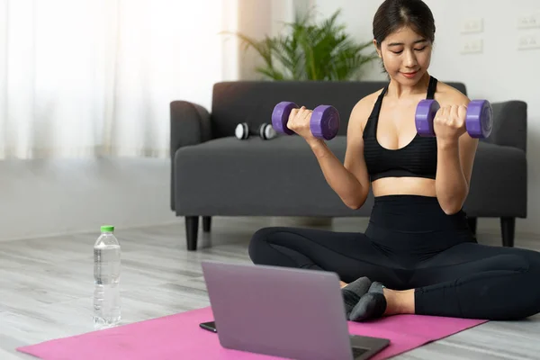 Joven mujer asiática haciendo ejercicios de fitness en casa a través de clase virtual — Foto de Stock