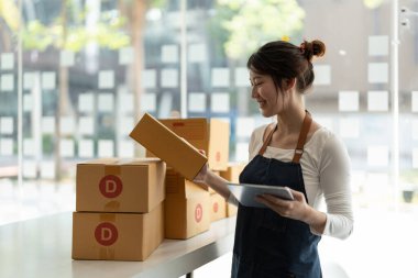 Genç iş kadını dükkanında online e-ticaret alışverişi yapıyor. Genç kadın satıcı müşteriye teslim etmek için bir paket ürün hazırla. Online satış, sme, e-ticaret.