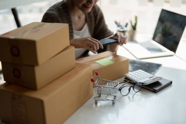 Genç Asyalı iş kadını eşyalarını topluyor ve karton kutunun üzerinde fotoğraf çekiyor. Genç Sahip Kadın Business Online 'a Başlıyor. Çevrimiçi alışveriş yapan KOBİ girişimcisi veya serbest çalışma kavramına sahip kişiler