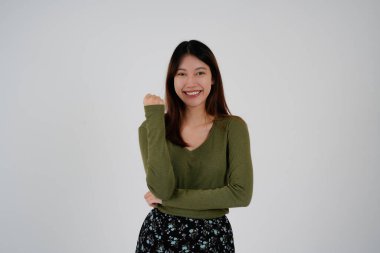 İzole edilmiş beyaz arka planda duran genç Asyalı kadın kameraya bakıp gülümsüyor. Pozitif kişi.