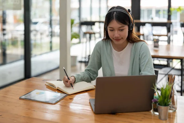 Mulher asiática escrevendo fazendo lista tomar notas em notepad trabalhando ou aprendendo no laptop indoors- curso educacional ou treinamento, seminário, conceito de educação on-line — Fotografia de Stock