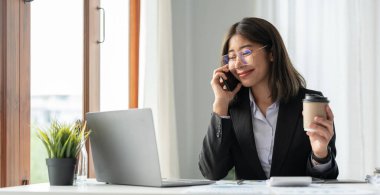 Akıllı telefonlu genç muhasebeci pazarlama danışmanlarını arayıp küresel iş piyasasındaki satış artışını analiz etmek için dizüstü bilgisayarı kullanıyor. muhasebe kavramı