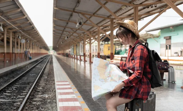 鉄道駅で鉄道プラットフォーム上の列車、アジアのバックパッカーを待っている間にマップするために探してバックパックを持つ若い女性旅行者。休日、旅、旅行、夏の旅行のコンセプト — ストック写真