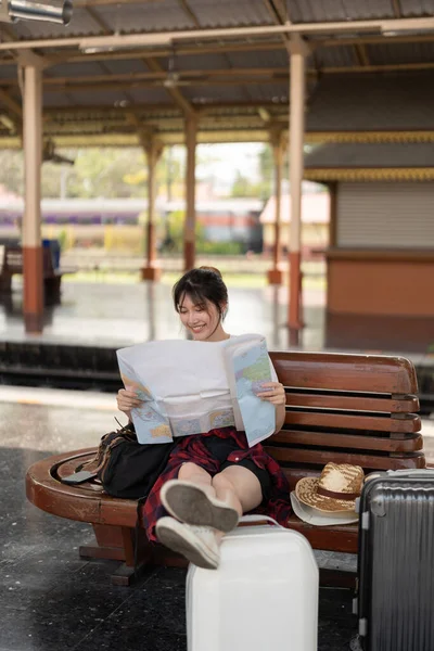 Jovem mulher asiática feliz viajante ou mochileiro usando mapa escolher onde viajar com bagagem na estação ferroviária, conceito de viagem de férias de verão — Fotografia de Stock