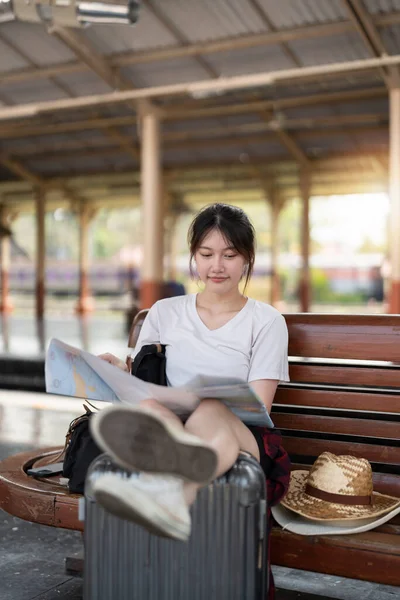 快乐的年轻亚洲女性旅行者或背包客使用地图选择在火车站带行李旅行的地方，暑假旅行的概念 — 图库照片