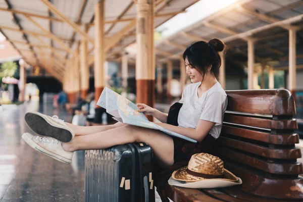 Harita kullanan mutlu genç Asyalı kadın gezgin veya gezgin tren istasyonunda valizlerle nereye gideceğinizi seçin, yaz tatili konsepti. — Stok fotoğraf