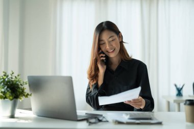 Genç Asyalı İş Kadını Ofiste Not Defteri ve cep telefonuyla arıyor, Finansal muhasebe kavramı.