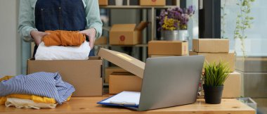 Genç Asyalı girişimci. Evde çalışan küçük işletme sahibi. Giysileri kutuya koyup teslim ediyor.