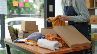 Young asian startup entrepreneur small business owner working at home, packaging clothes in box and delivery situation