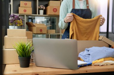 Genç Asyalı girişimci evde çalışan küçük işletme sahibi, paketleme ve teslimat durumu.