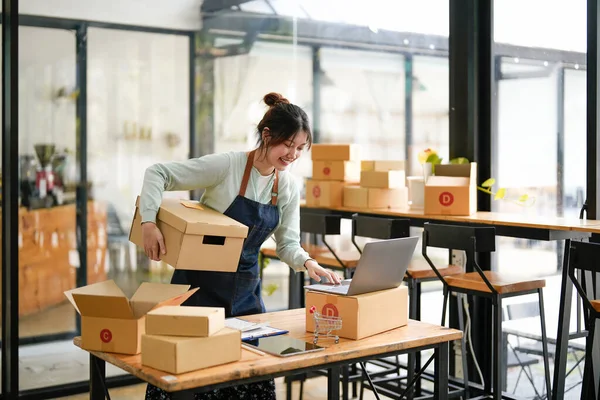 Başlangıçta küçük işletme KOBİ 'si, laptop kullanan girişimci paket ürün kutusu hazırlamak için online alışveriş siparişi alıyor ve kontrol ediyor. Çevrimiçi fikirler satılıyor
