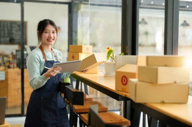 Başlangıçta küçük işletme KOBİ 'si, laptop kullanan girişimci paket ürün kutusu hazırlamak için online alışveriş siparişi alıyor ve kontrol ediyor. Çevrimiçi fikirler satılıyor