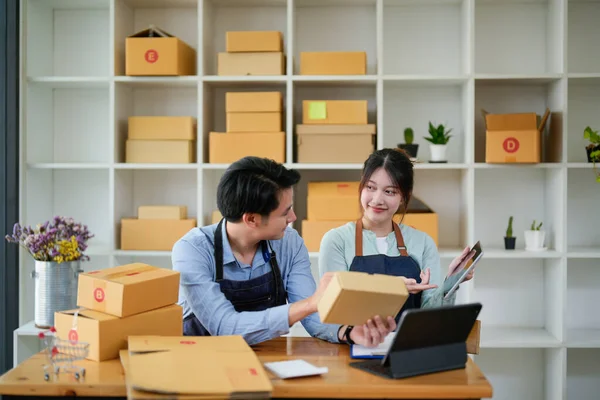 创业的小企业主在工作场所与平板电脑打交道。自由应聘的男女卖家检查产品定单，包装货物以交付顾客。网上销售、电子商务、航运概念 — 图库照片