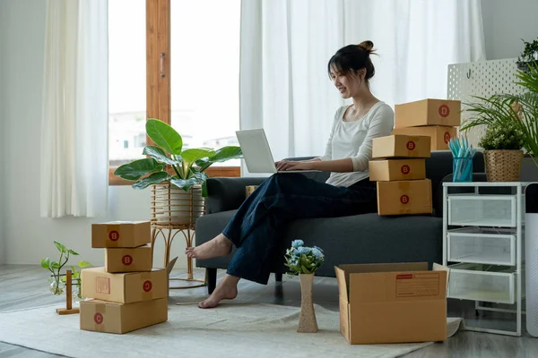 İş yerinde bilgisayarla çalışan küçük bir işletme sahibi. Serbest kadın satıcı dizüstü bilgisayardan siparişleri kontrol ediyor. Müşteriye teslimat için mal paketliyorum. Çevrimiçi satış. E-ticaret