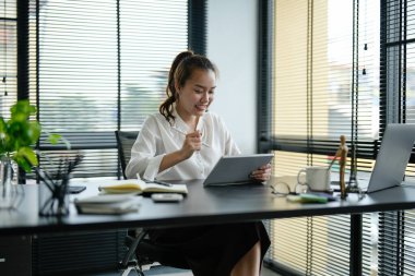 Genç Asyalı iş kadını ofiste dizüstü bilgisayarla çalışıyor.