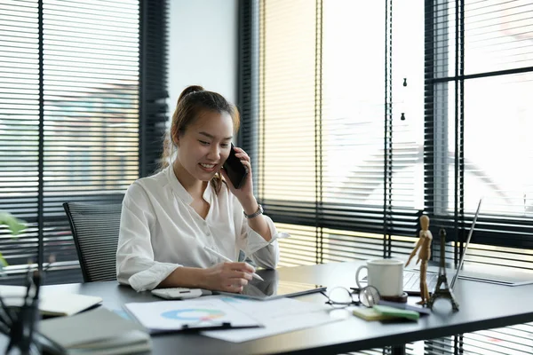 Πορτρέτο ασιατική επιχειρηματίας κάνει ένα τηλεφώνημα και χαμογελώντας, ενώ εργάζονται στο γραφείο — Φωτογραφία Αρχείου