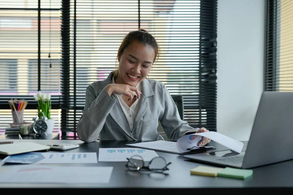 İş dünyasından Asyalı kadın mali belge grafikleri ve grafiklerini ofiste analiz etmeyi planlıyor