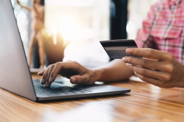 Kredi kartı tutan genç bayanı kapatın ve online alışveriş için dizüstü bilgisayar kullanın. Çevrimiçi ödeme alışveriş kavramı