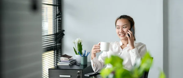 Νεαρή Ασιάτισσα επιχειρηματίας όμορφη γοητευτική χαμογελαστή και καλώντας με κινητό τηλέφωνο στο γραφείο — Φωτογραφία Αρχείου