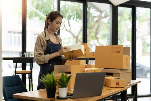 Стартап SME невеликий бізнес підприємець SME або фрилансер азіатська жінка використовує ноутбук з коробкою, онлайн маркетинговий пакет коробки і доставки, концепт SME — стокове фото