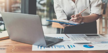 İş kadınları muhasebecisi el bilgisayarı ve hesap makinesi kullanır. Çalışma odasındaki beyaz masanın üzerindeki vergiyi hesaplar.