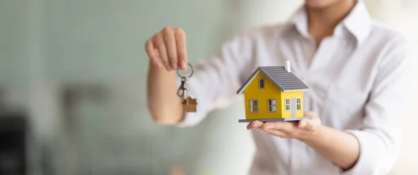 Tiro recortado de agente imobiliário entregando chaves e modelo de casa. — Fotografia de Stock