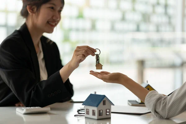 Agente imobiliário segurando casa chave para seu cliente após a assinatura de contrato no escritório, conceito para imóveis, mudança de casa ou arrendamento de propriedade — Fotografia de Stock