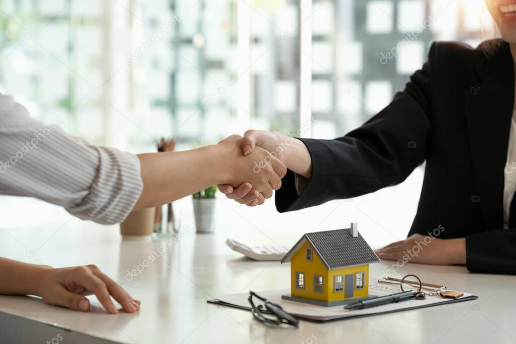 Real estate broker and customer shaking hands after signing a contract: real estate, home loan and insurance concept